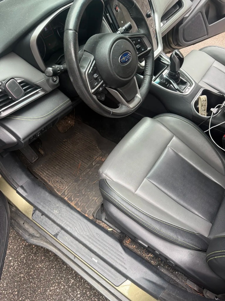 Subaru interior before detailing — muddy floor mat and debris in crevices